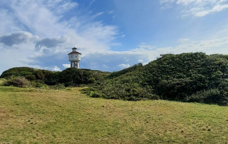 Wassertum auf Langeoog vor blauem Himmel und hinter grünen Dünen im Sommer